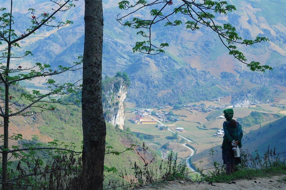 Una donna in abito tradizionale osserva una valle da una strada di montagna