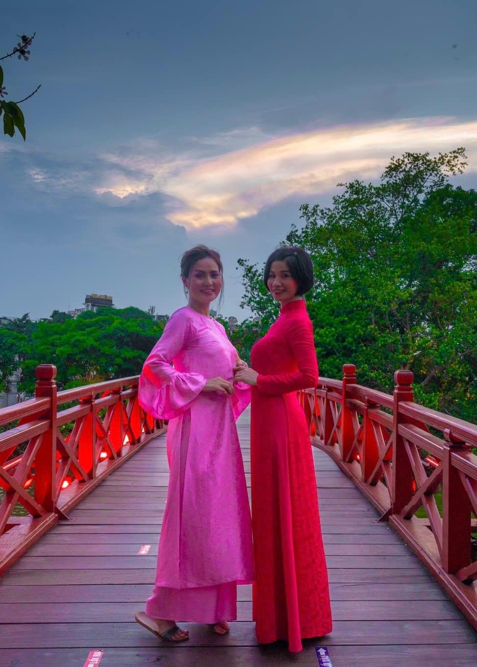 Viaggiatori in ao dai su un ponte rosso al tramonto, in Indocina