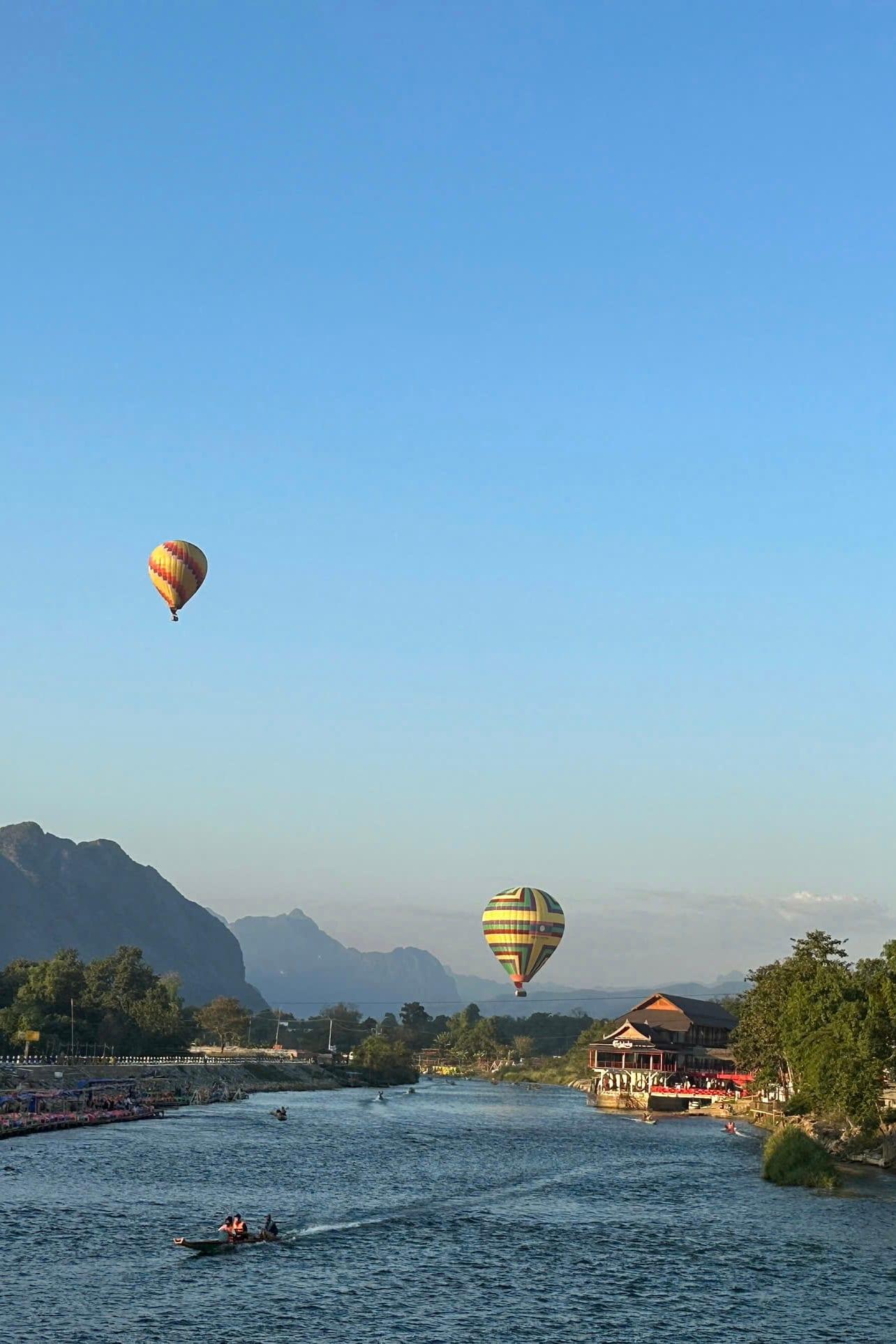 Due mongolfiere che fluttuano sopra una valle fluviale circondata da picchi calcarei