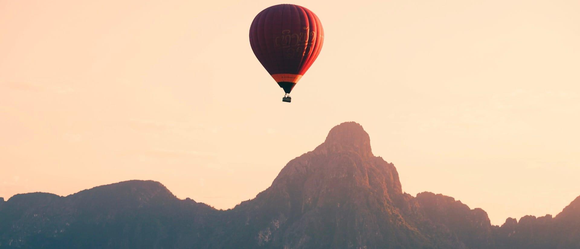 Una mongolfiera che fluttua all’alba sopra montagne carsiche calcaree