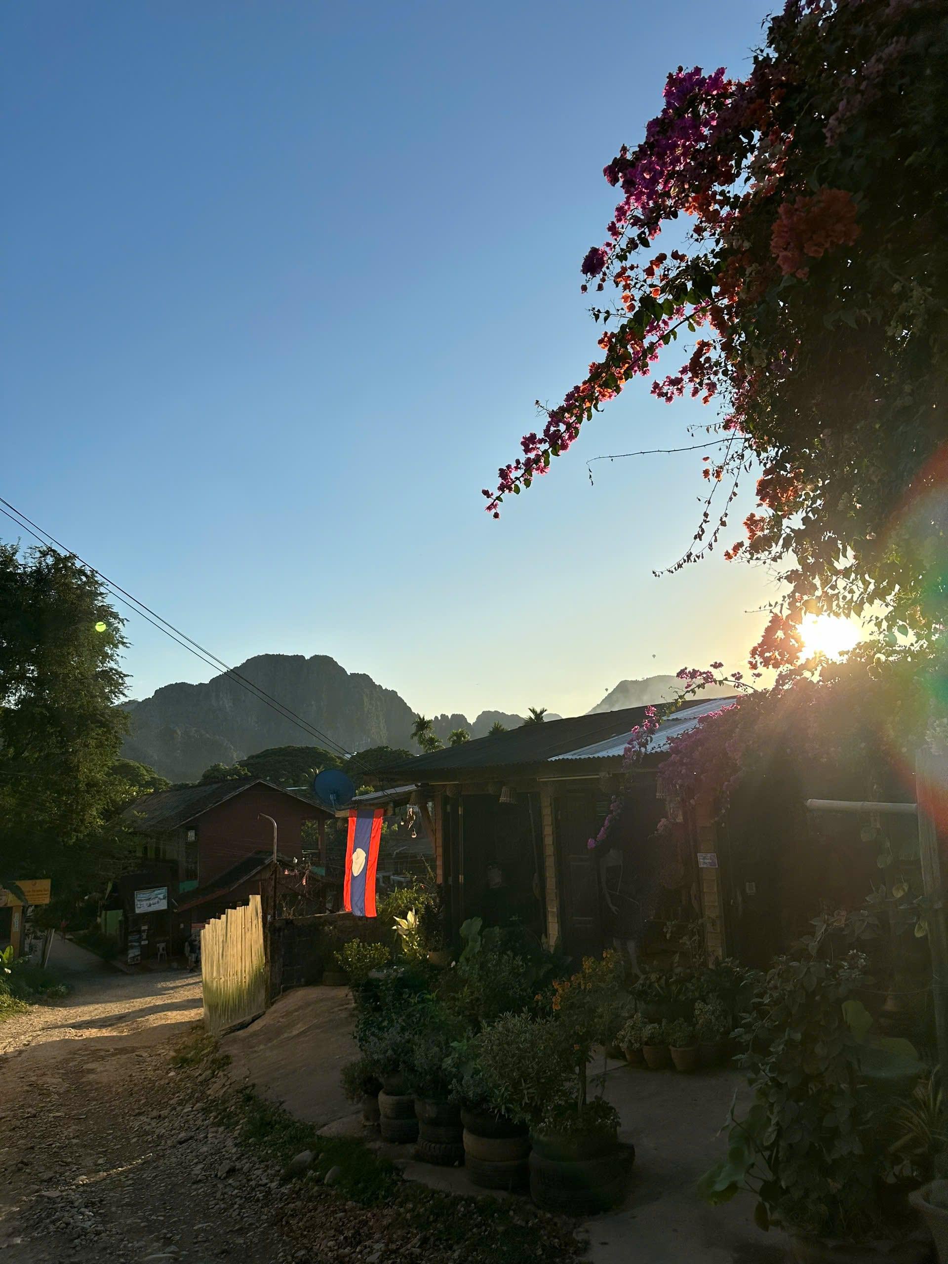 Una strada di villaggio al tramonto, con picchi calcarei dietro i tetti