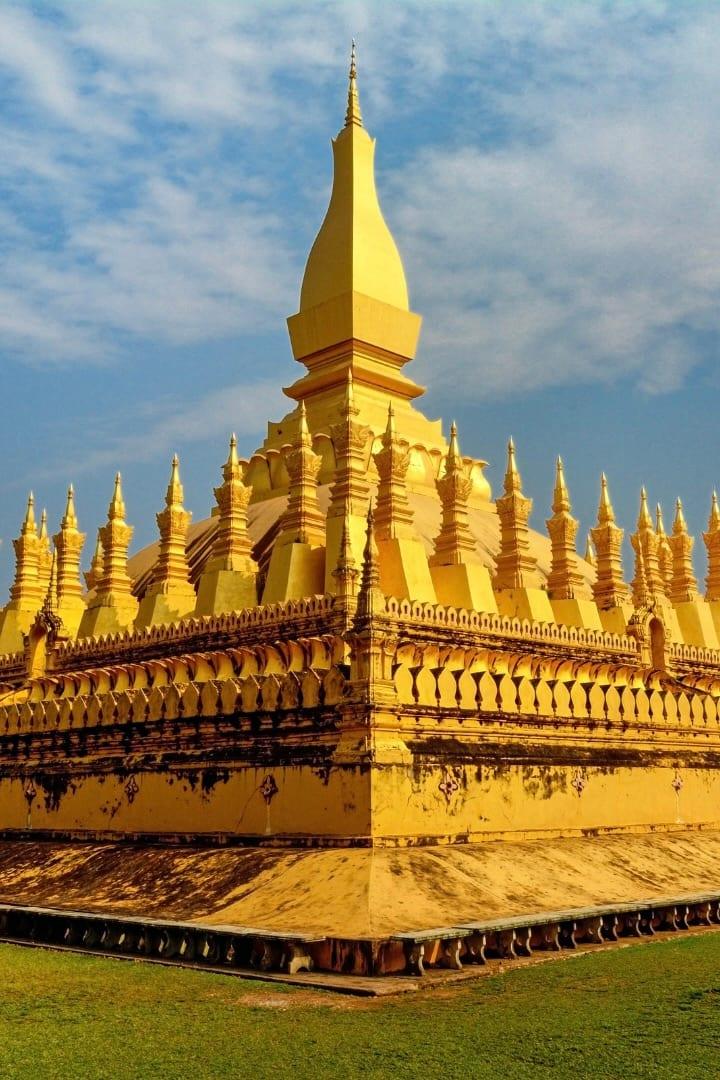 Uno stupa dorato con un’alta guglia circondata da file di guglie più piccole, su un prato sotto il cielo azzurro