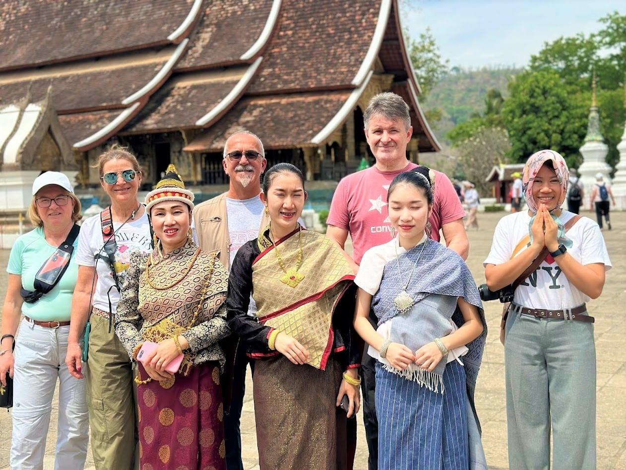 Gruppo con ragazze in abito tradizionale laotiano davanti a un tempio di Luang Prabang