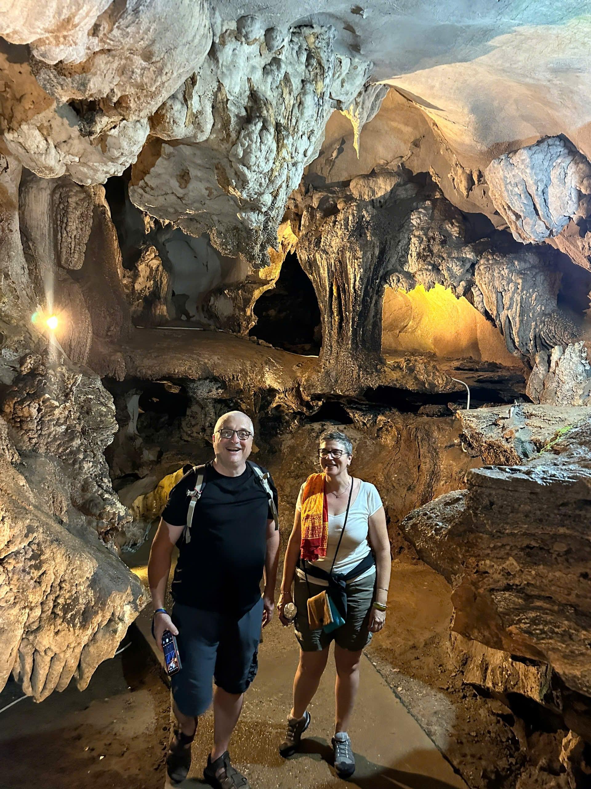 Due viaggiatori con lo zaino attraversano un’ampia sala di una grotta